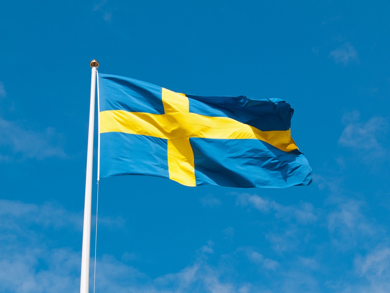 Svensk flagga som vajar mot blå himmel