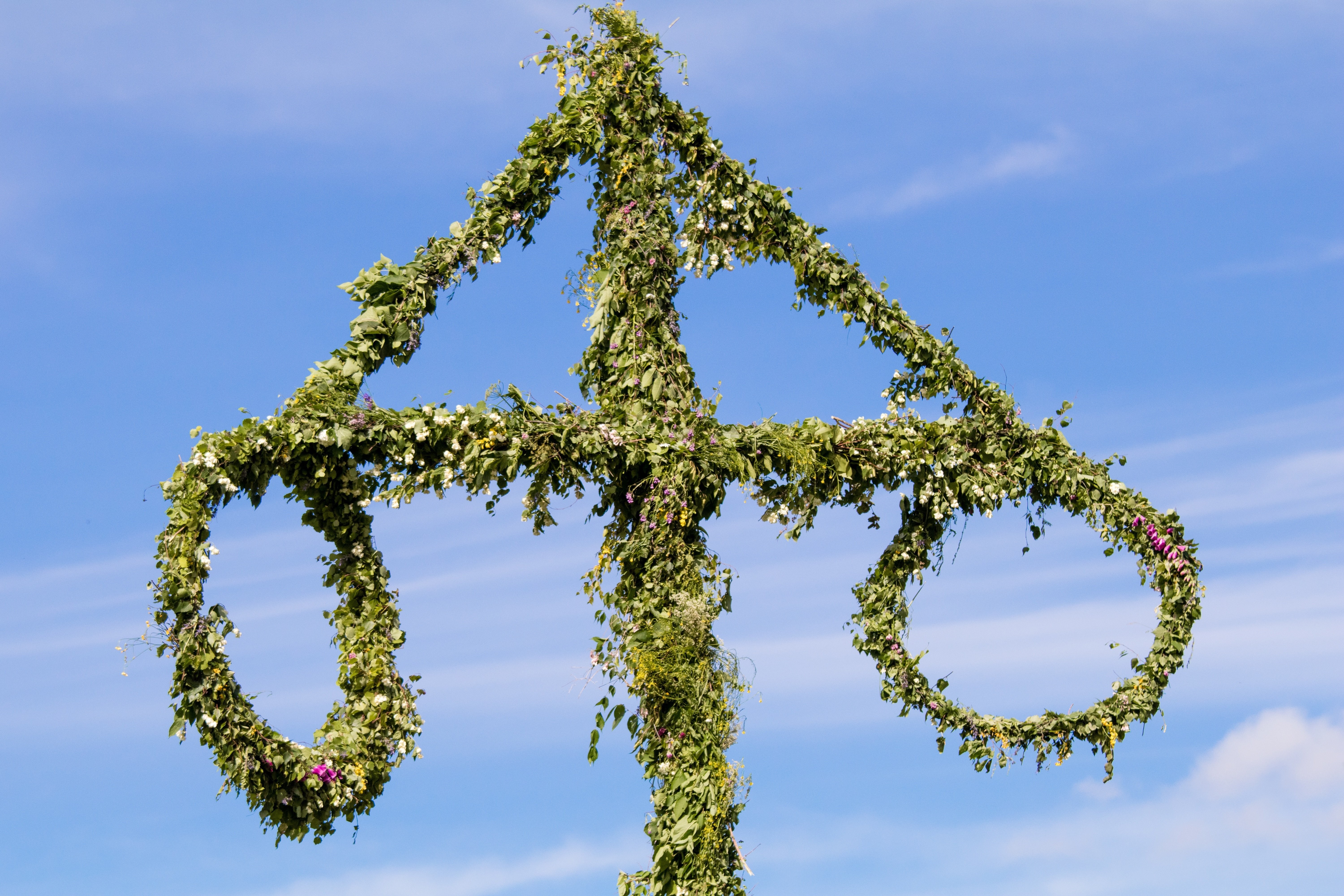 Bild på en med blommor klädd midsommarstång