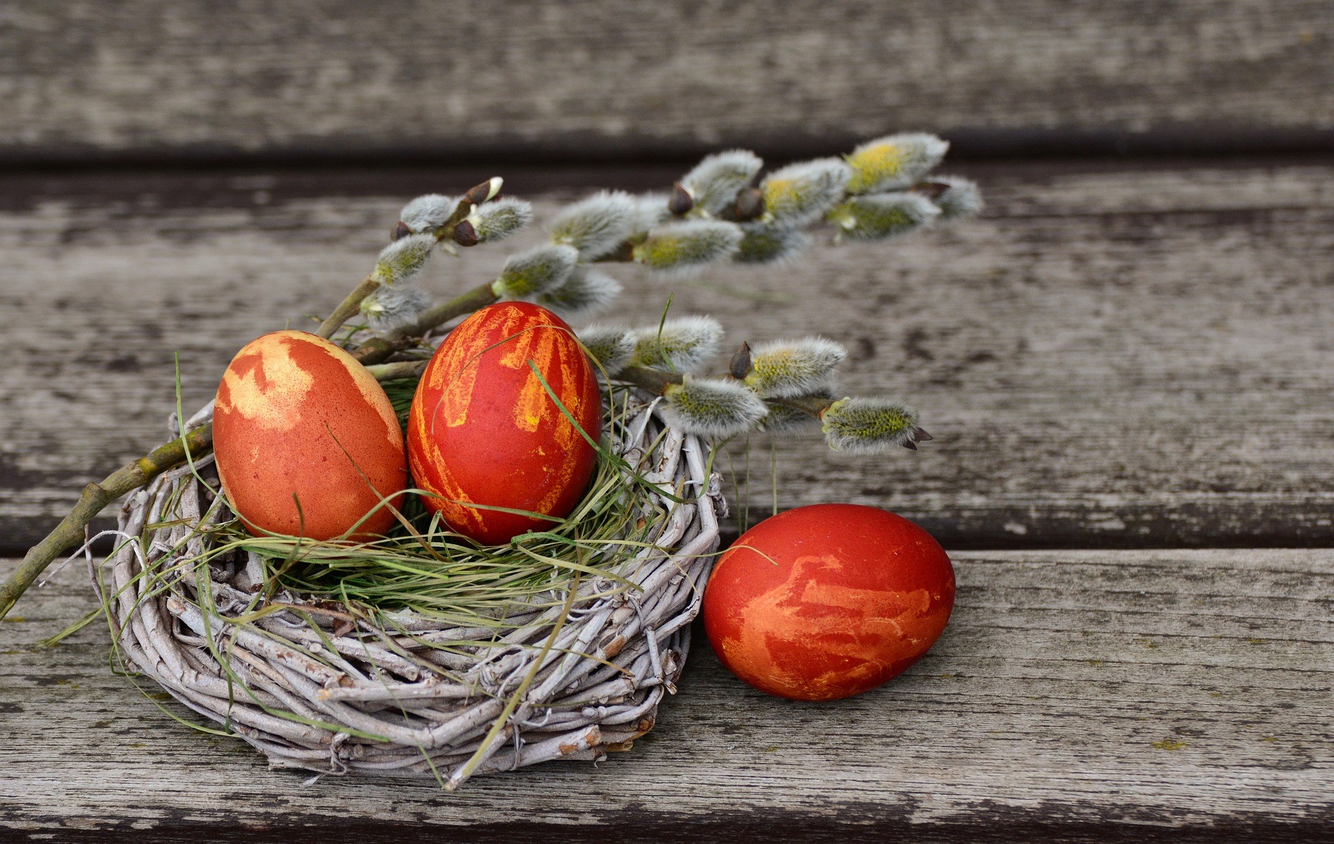 Bild på 3 rödmålade ägg som ligger i en krans med vide